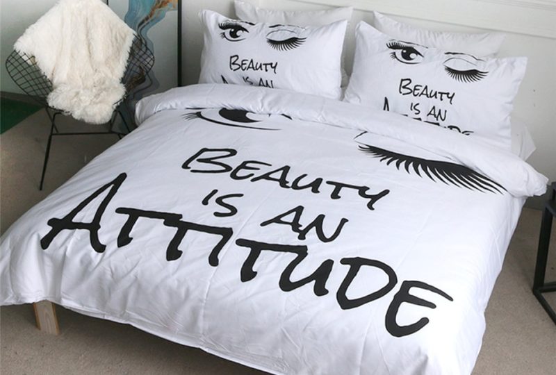 53056-13ddb4.jpg Parure de lit motif cils et inscription « Beauty is an Attitude ». Bonne qualité, confortable et à la mode sur un lit dans une maison