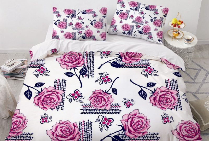 Parure de lit blanche parsemée de roses. Bonne qualité, confortable et à la mode sur un lit dans une maison
