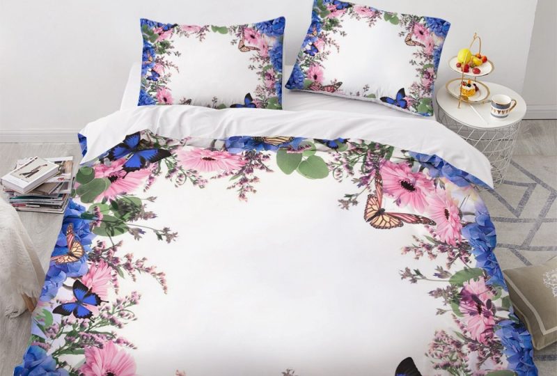Parure de lit blanche encadrée de motifs fleurs et papillons. Bonne qualité, confortable et à la mode sur un lit dans une maison