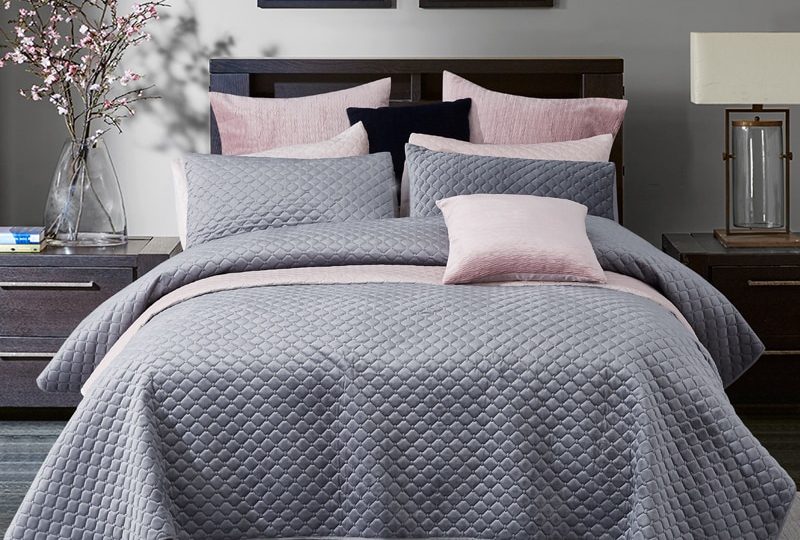 Parure de lit grise à motifs géométriques en relief. Bonne qualité, confortable et à la mode sur un lit dans une maison