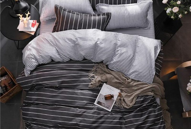 Parure de lit noir à rayures blanches. Bonne qualité, confortable et à la mode sur un lit dans une maison