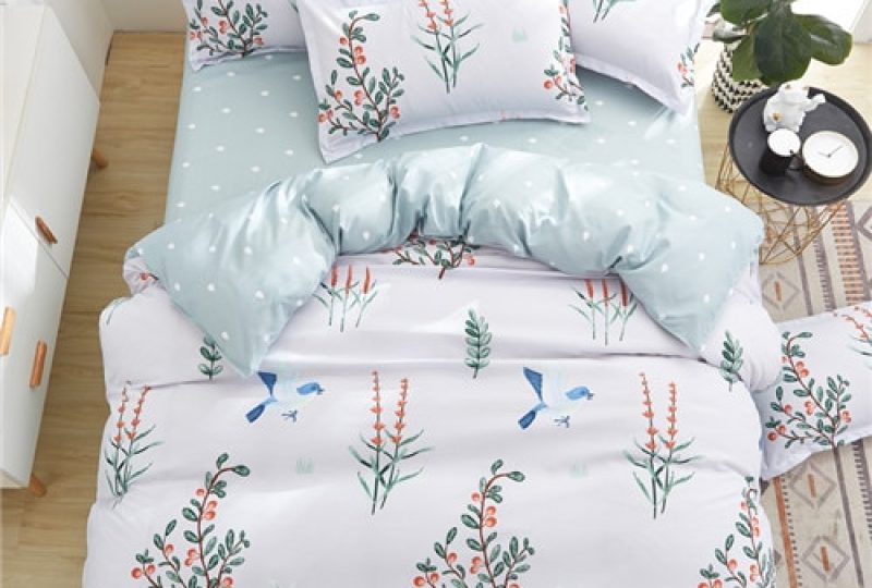 Parure de lit blanche avec imprimé oiseaux et fleurs de printemps. Bonne qualité, confortable et à la mode sur un lit dans une maison