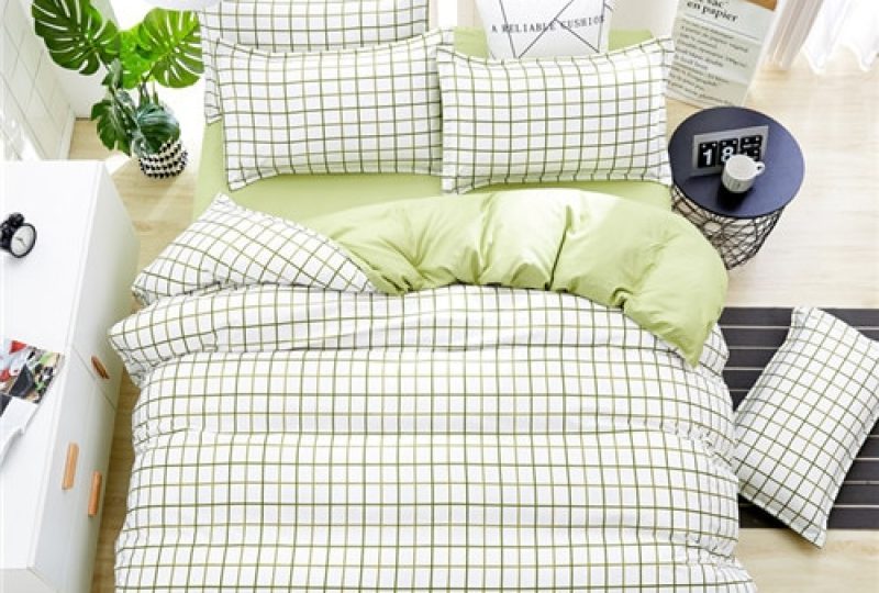 Parure de lit blanche à motifs carreaux verts. Bonne qualité, confortable et à la mode sur un lit dans une maison