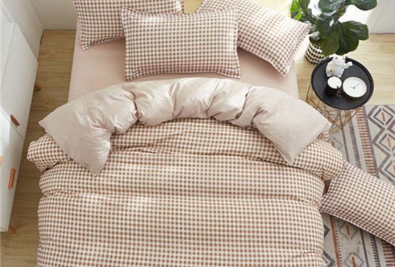 Parure de lit marron à motif carreaux blancs. Bonne qualité, confortable et à la mode sur un lit dans une maison