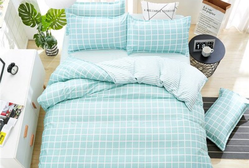 Parure de lit bleu clair à motifs carreaux blancs. Bonne qualité, confortable et à la mode sur un lit dans une maison