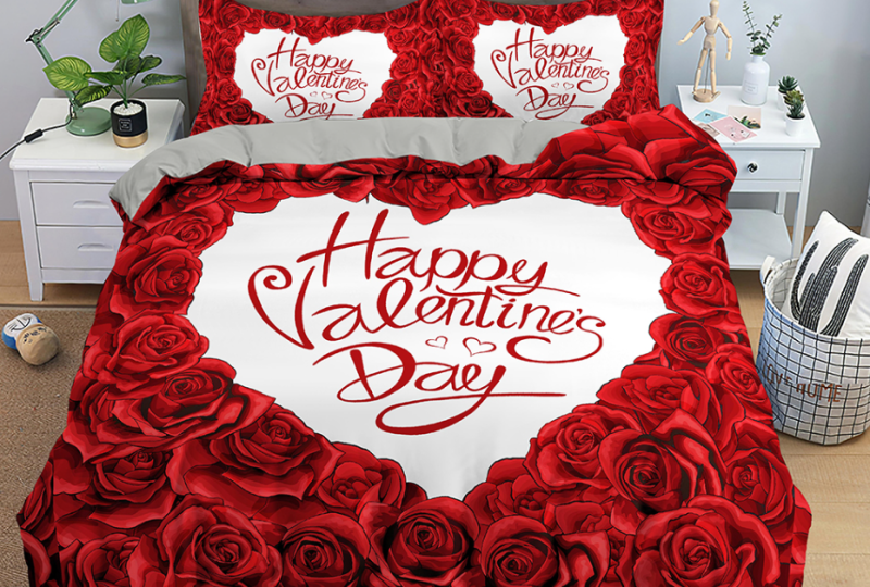 parure de lit de lit en roses rouges formant un cœur blanc à l'intérieur duquel il est écrit un message en anglais pour souhaiter une joyeuse saint valentin en rouge, il y a une table de chevet blanche de chaque côté du lit
