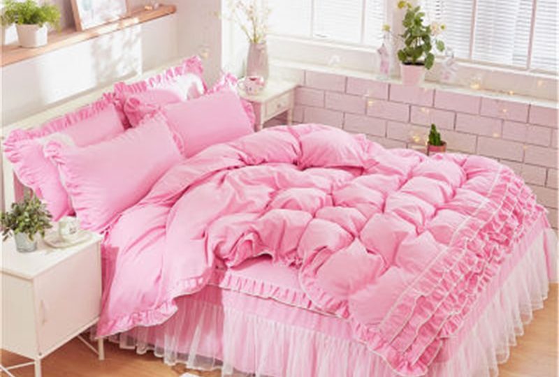 Parure de lit rose à dentelle. Bonne qualité, confortable et à la mode sur un lit dans une maison