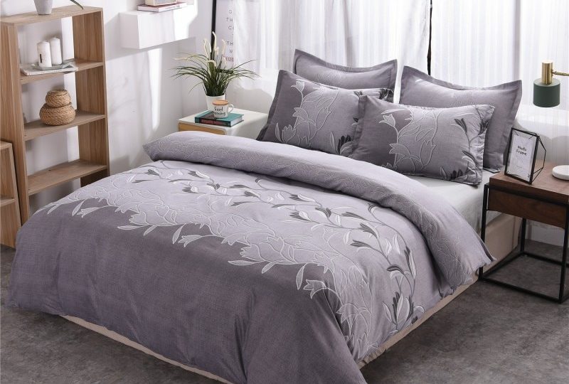 Parure de lit grise à motif floral unique. Bonne qualité, confortable et à la mode sur un lit dans une maison