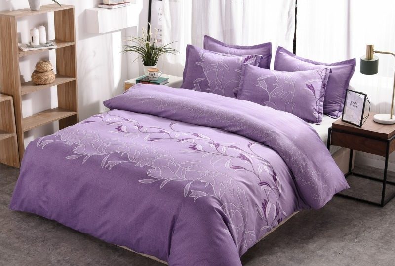 Parure de lit violette à motif floral unique. Bonne qualité, confortable et à la mode sur un lit dans une maison
