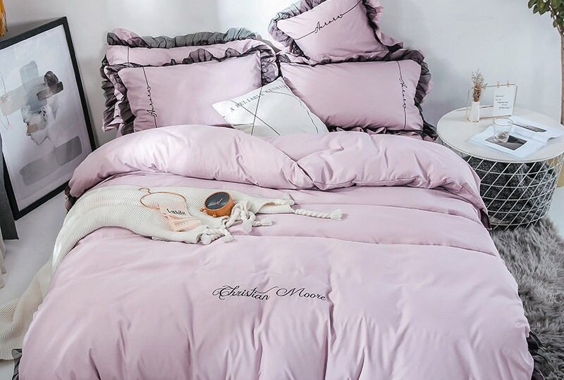 Parure de lit rose-blanc contour marron. Bonne qualité, confortable et à la mode sur un lit dans une maison