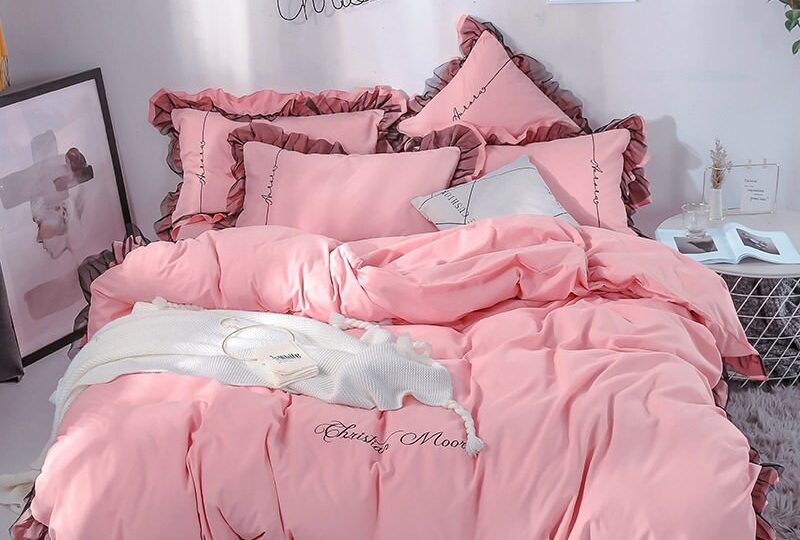 Parure de lit rose dragée contour marron. Bonne qualité, confortable et à la mode sur un lit dans une maison