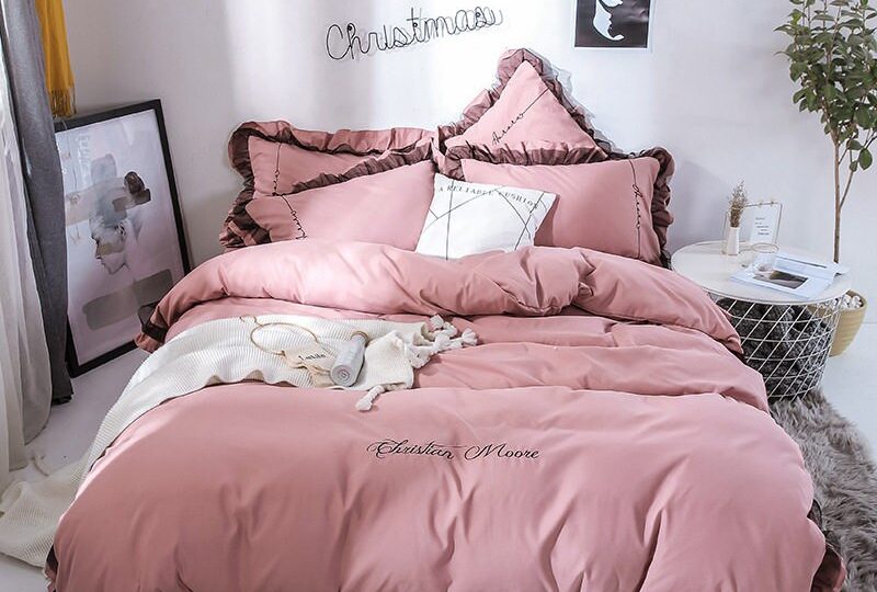 Parure de lit rose contour marron. Bonne qualité, confortable et à la mode sur un lit dans une maison