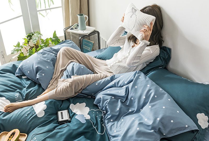 Parure de lit vert foncé avec imprimé nuages. Bonne qualité, confortable et à la mode sur un lit dans une maison