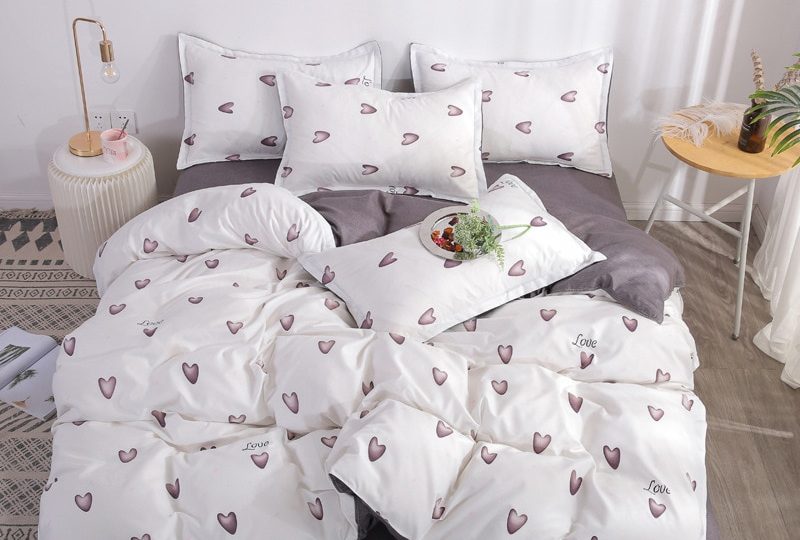 54769-376e08.jpg Parure de blanche avec imprimés cœurs violets. Bonne qualité, confortable et à la mode sur un lit dans une maison
