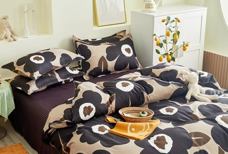 Parure de lit beige avec imprimé fleurs noires. Bonne qualité, confortable et à la mode sur un lit dans une maison