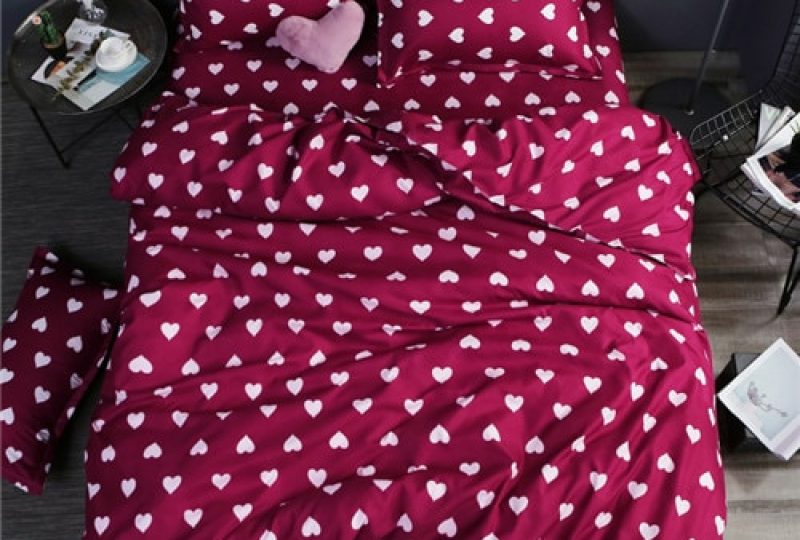 Parure de lit bordeaux avec imprimés cœurs blancs. Bonne qualité et à la mode sur un lit dans une maison