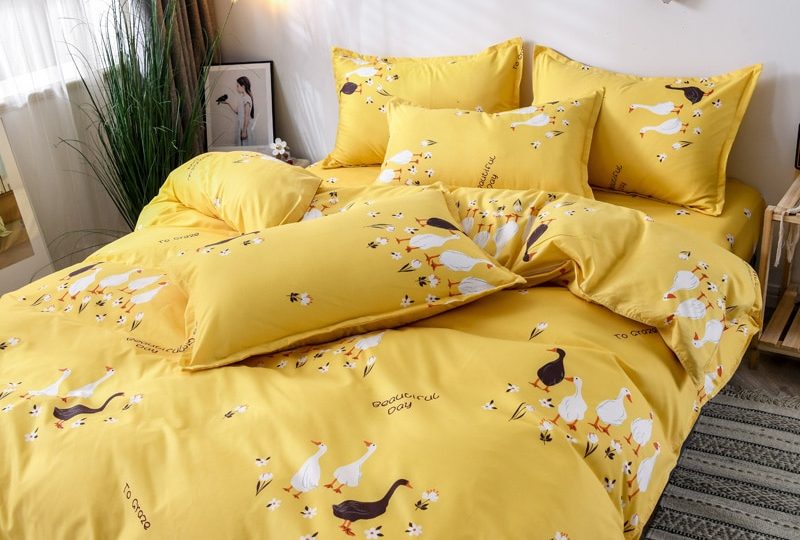 Parure de lit jaune avec imprimés oie. Bonne qualité, confortable et à la mode sur un lit dans une maison