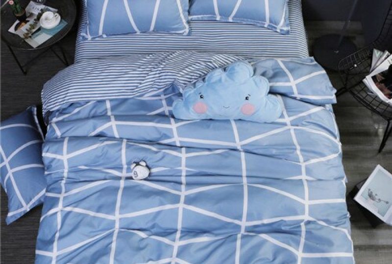 Parure de lit bleu à motifs géométriques blancs. Bonne qualité, confortable et à la mode sur un lit dans une maison