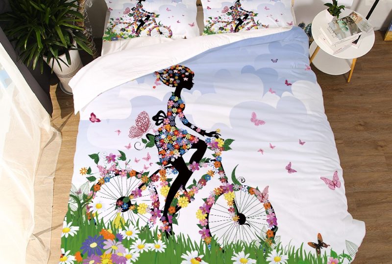 Parure de lit blanche à motif fille à vélo couverte de fleurs. Bonne qualité, confortable et à la mode sur un lit dans une maison