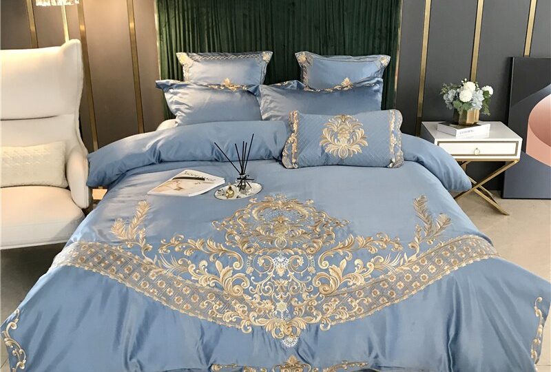 Parure de lit gris bleu brodée en satin. Bonne qualité, confortable et à la mode sur un lit dans une maison