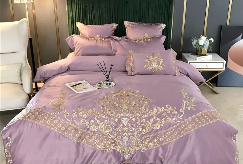 Parure de lit violette brodée en satin. Bonne qualité, confortable et à la mode sur un lit dans une maison
