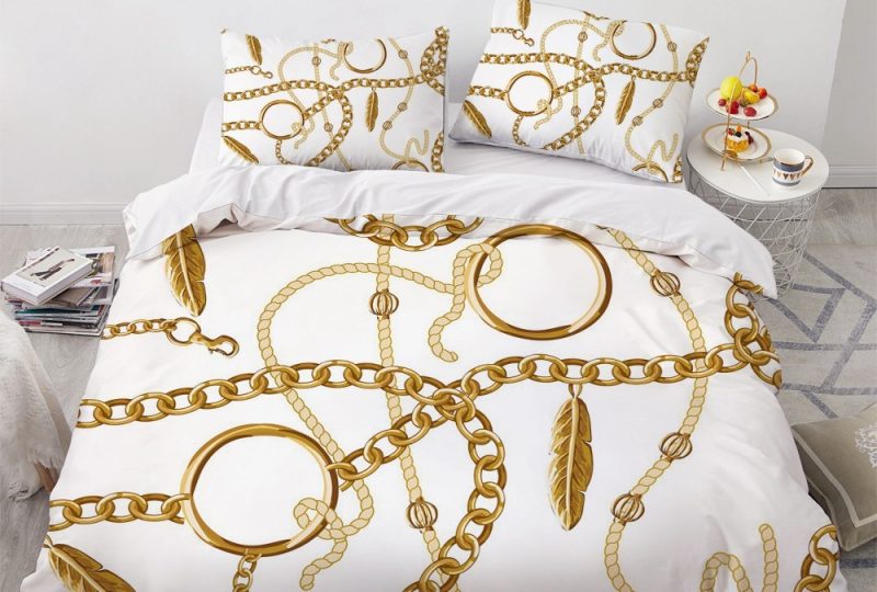 Parure de lit blanche avec imprimé chaîne en or. Bonne qualité, confortable et à la mode sur un lit dans une maison