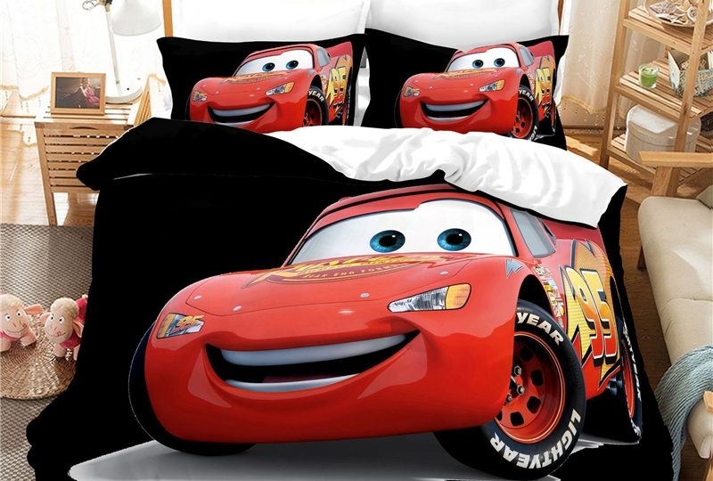 Parure de lit Cars rouge sur fond noir installée sur le lit d'une chambre d'enfant , avec à gauche une table de chevet et à droite des étagères en bois