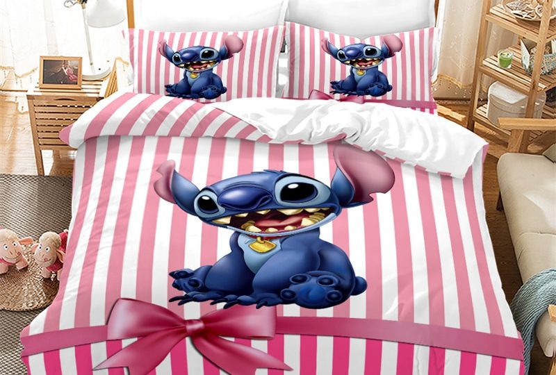 Dans une chambre le lit est décoré d'une parure à l'effigie du petit personnage Stitch bleu, le reste de la couverture est rayé verticalement en rouge est blanc et au bas de la couverture il y a un ruban avec un noeud comme pour un cadeau, les coussins sont assortis, à droite du lit il y a un banquette en bois avec les coussins blanc, et un meuble étagère en bois, à gauche du lit il y a une table de chevet en bois et des jouets