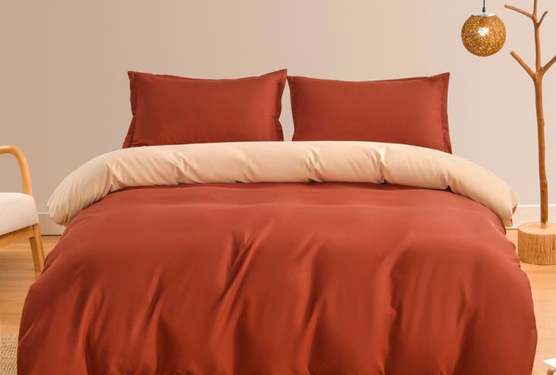 Parure de lit terracotta à couleur unie dans une chambre au mur beige et un sol en osier