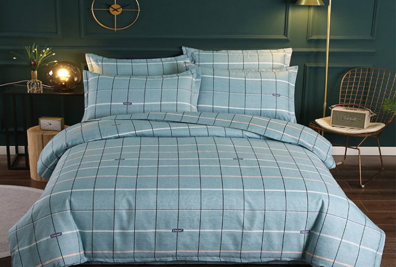 Parure de lit turquoise à carreaux chique en tissu. Bonne qualité, confortable et à la mode sur un lit dans une maison