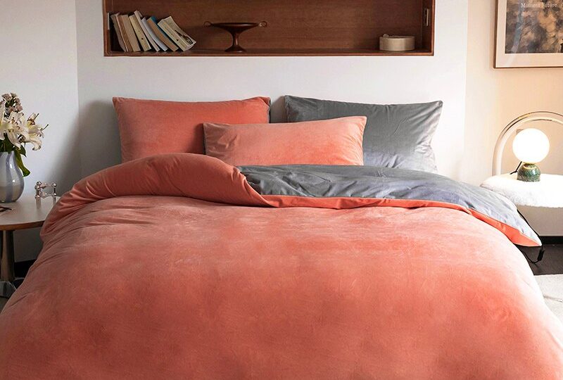 Parure de lit en couleur unie terracotta dans une chambre au mur blanc et sol en tapis gris