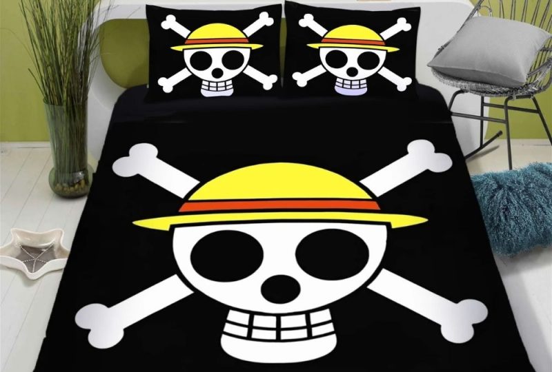 Parure de lit logo One Piece sur un ensemble noir avec deux coussins assortis. Le mur à la tête de lit est vert pomme, une chaise à droite, un meuble blanc derrière la tête de lit.