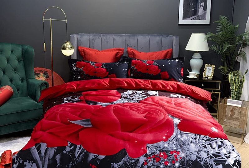 Parure de lit romantique de couleur noir avec des motifs de roses rouges dans une chambre au mur noir et au sol en couleur bois parquet
