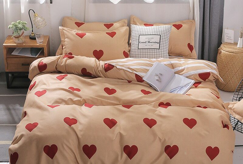 Parure de lit beige avec coeurs rouges. Bonne qualité, confortable et à la mode sur un lit dans une maison