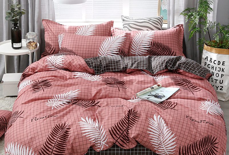 Solstice-parure-de-lit-imprim-e-rayures-noires-et-blanches-housse-de-couette-taie-d-oreiller Parure de lit moderne rose avec des motifs de feuillages de couleurs noires et blanches, avec un magazine posé dessus dans une chambre devant une fenêtre