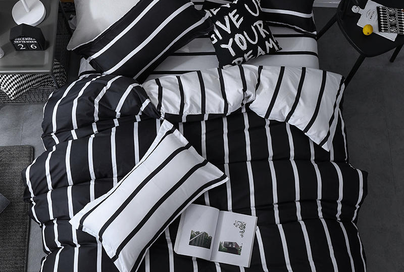 Parure de lit moderne de couleur noire et aux rayures blanches dans une chambre au sol gris