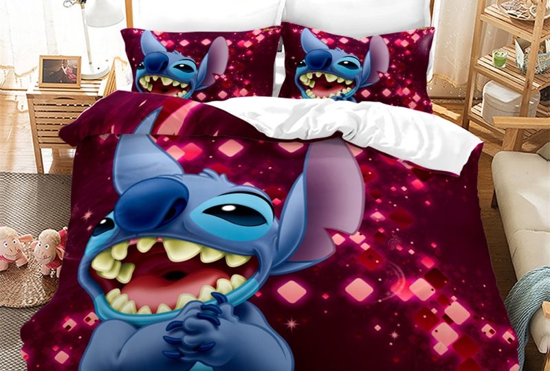 Dans une chambre le lit est décoré d'une parure à l'effigie du personnage de Stitch qui rigole, le reste de la couverture est rouge pourpre, les coussins sont assortis, à droite du lit il y a un banquette en bois avec les coussins blanc, et un meuble étagère en bois, à gauche du lit il y a une table de chevet en bois et des jouets