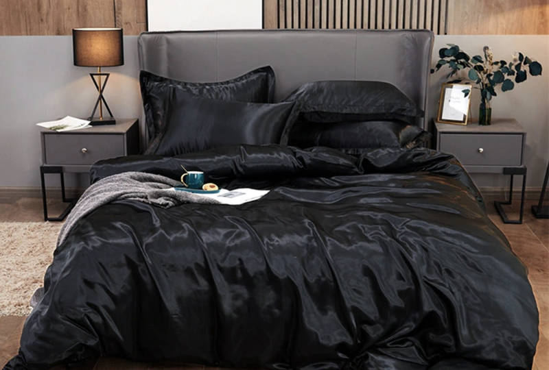 Parure de lit satiné noir. Bonne qualité et à la mode sur un lit dans une maison