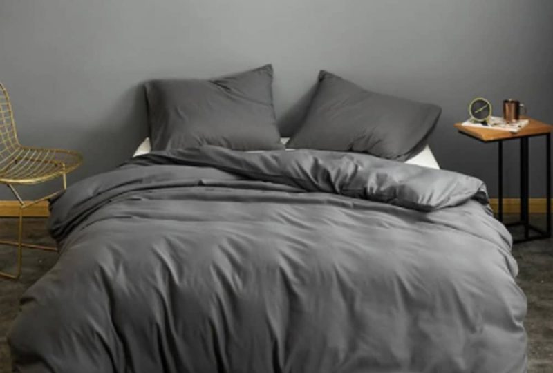 Parure de lit grise unie. Bonne qualité, confortable et à la mode sur un lit dans une maison