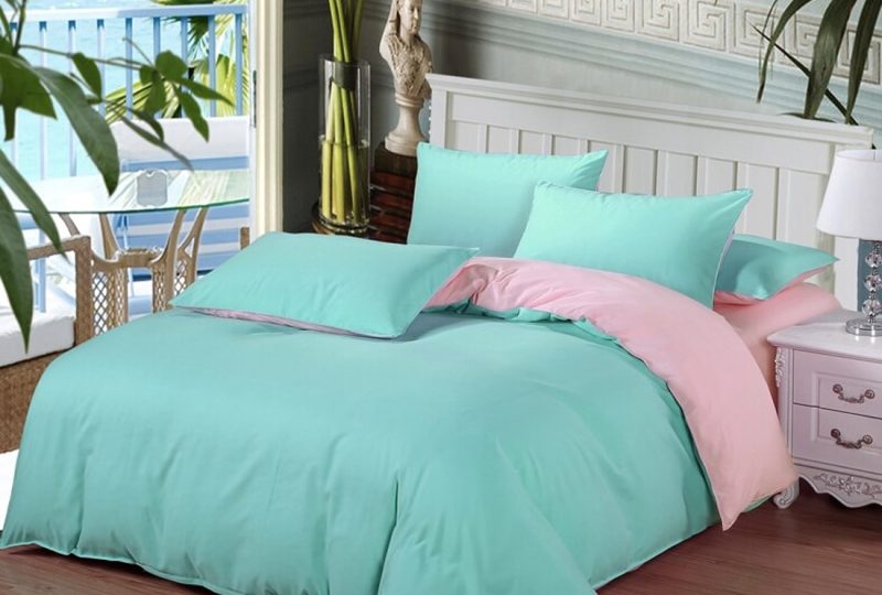 Parure de lit bleu turquoise et rose. Bonne qualité, confortable et à la mode sur un lit dans une maison